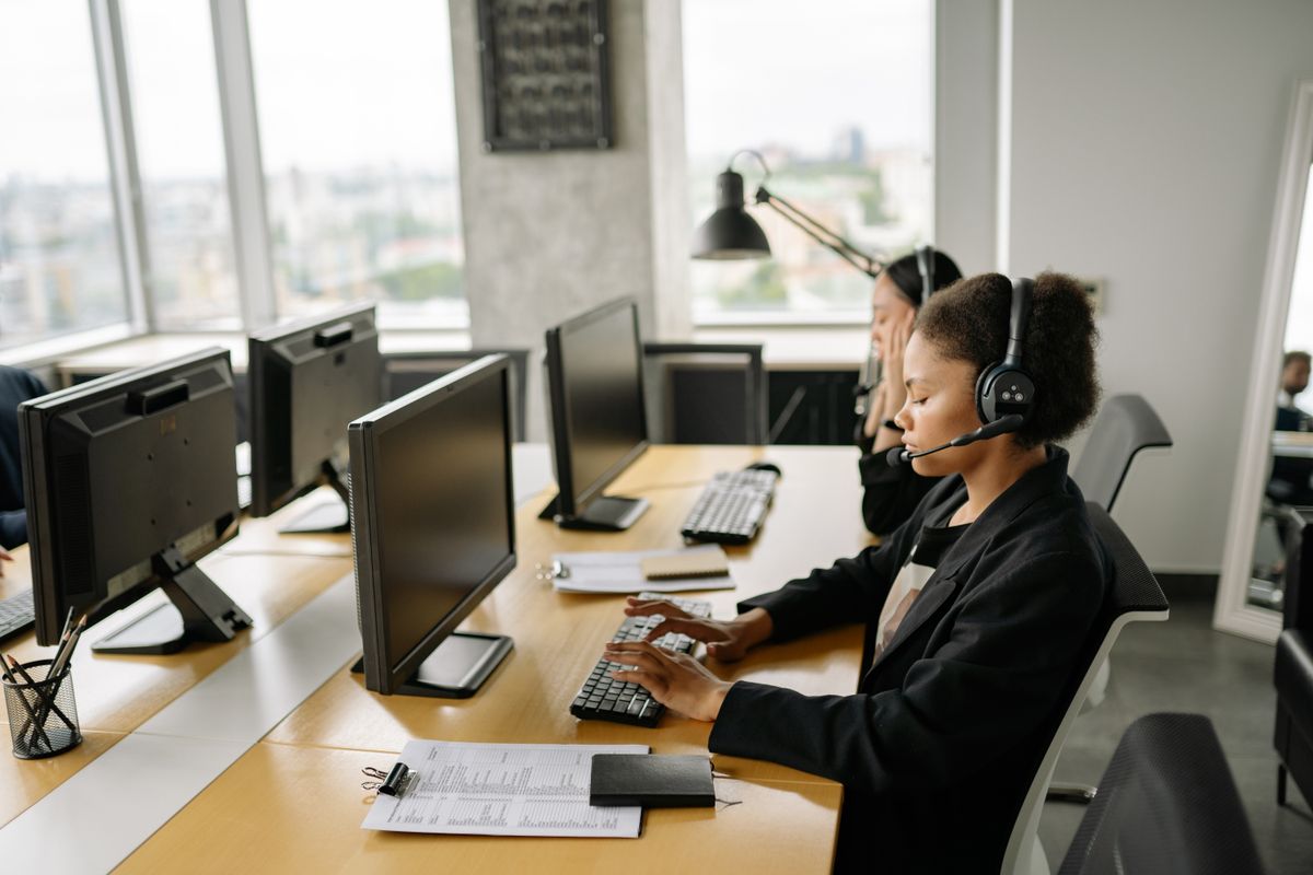 Team of customer support agents wearing headsets working at desks in a call center