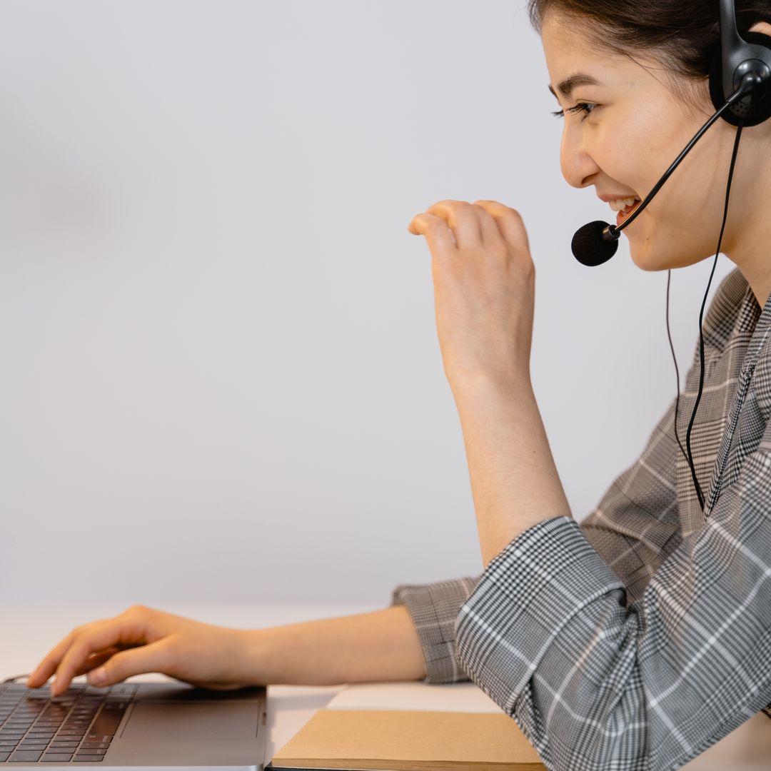 Smiling support agent in a call center working on a laptop with a headset