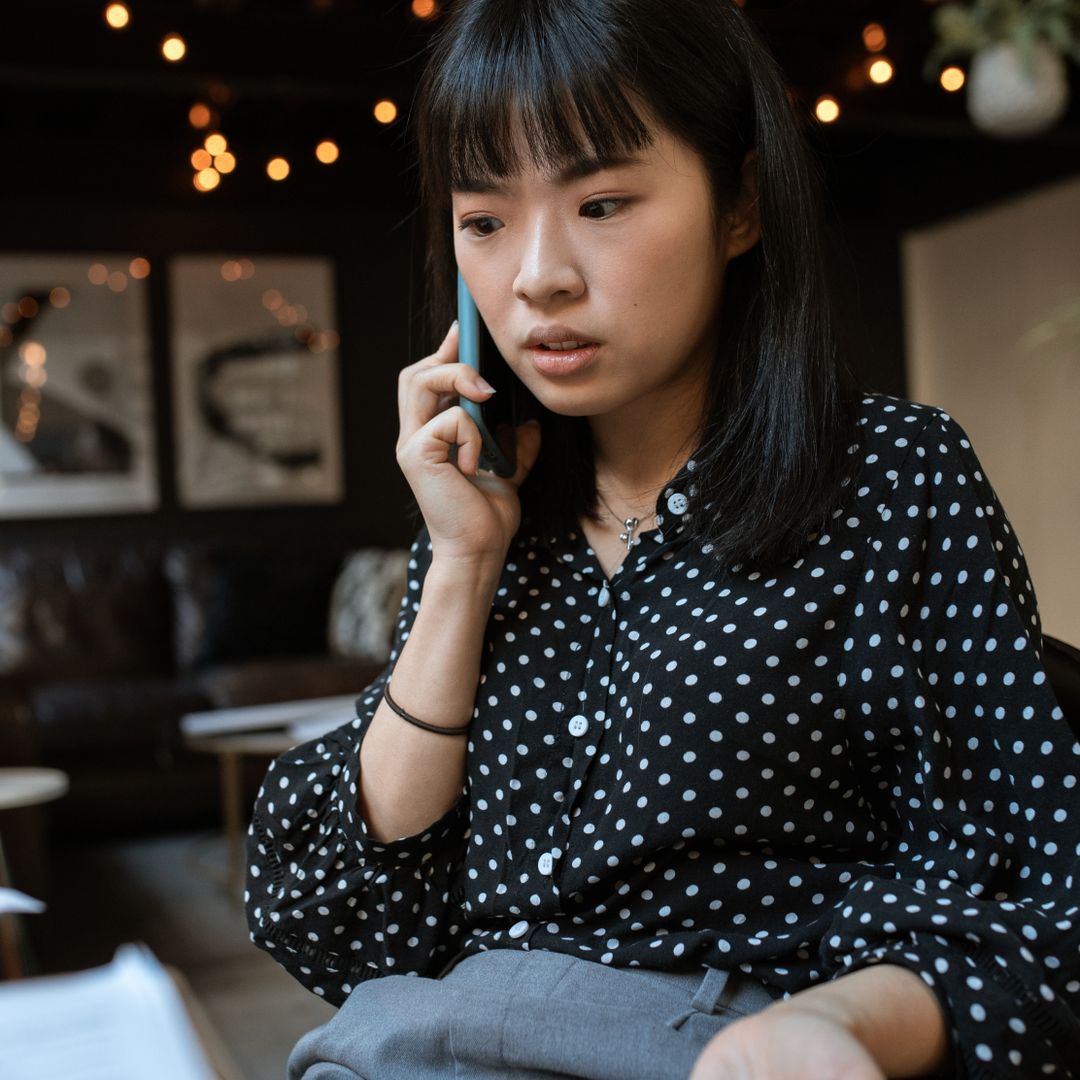 Young woman taking a business call on her smartphone indoors