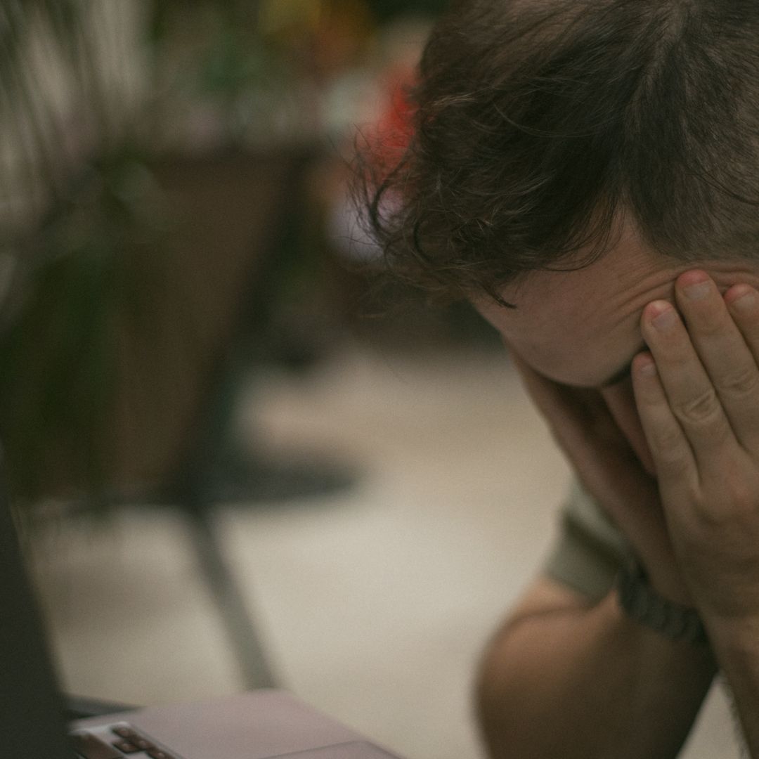 Close-up of an exhausted man with his head buried in his hands