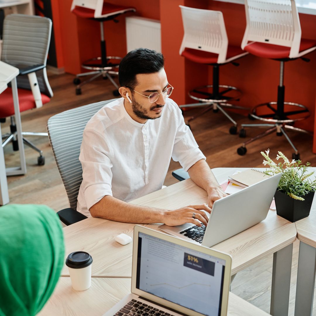 Business professionals collaborating over laptops and coffee in a modern office