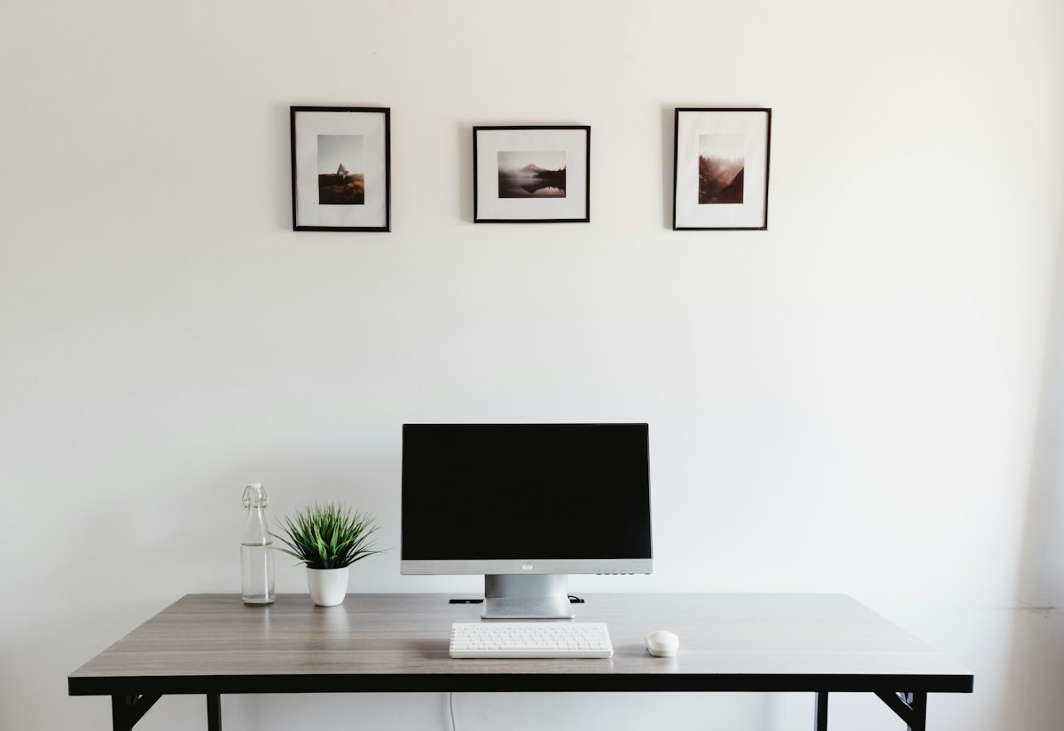 A tidy home office desk setup with dual monitors, planner, and headset for virtual assistance work