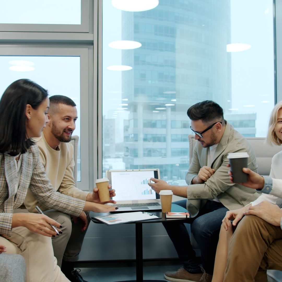 Diverse marketing team discussing around a laptop in an office