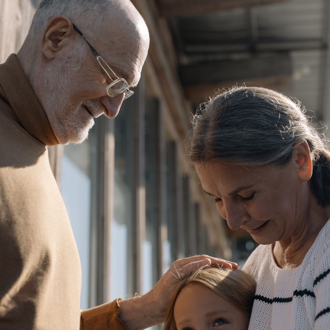 Grandparents smiling while their young grandchild hugs them