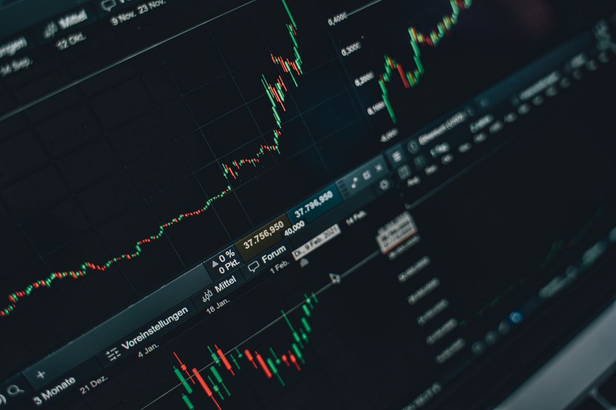 Multiple investment graphs displayed across laptop screens