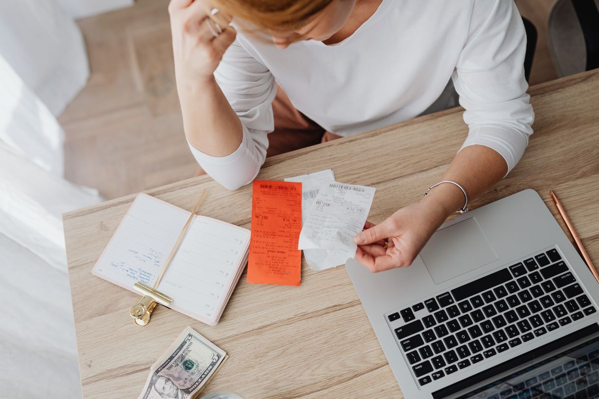 Woman reviewing receipts and planning budget with a laptop at home