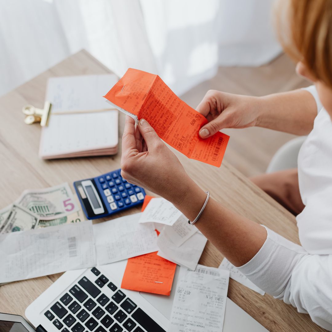 Woman using calculator with receipts at a home office desk