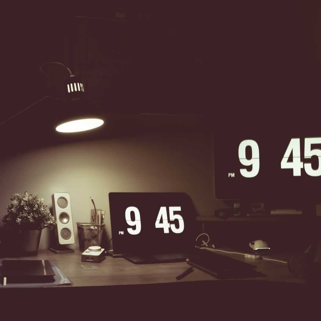 Cozy low-light desk with digital clocks and modern devices
