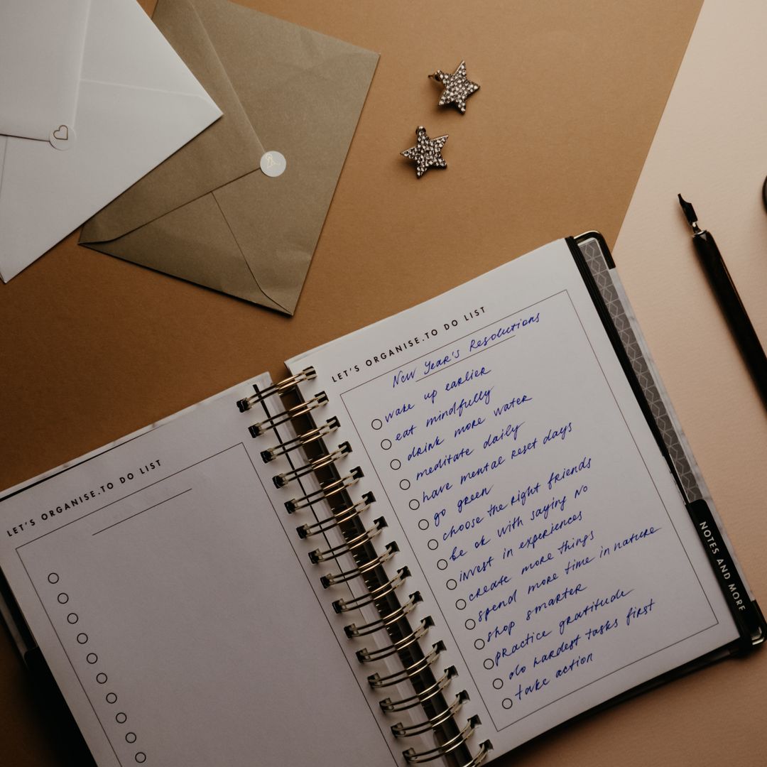 An elegant flat lay of a planner, fountain pen, and envelopes