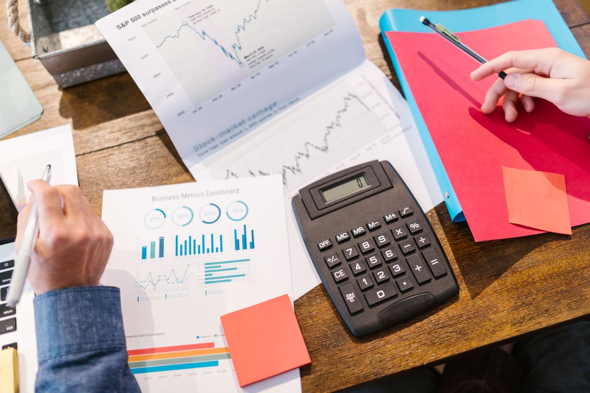 A calculator with financial documents and charts on a desk