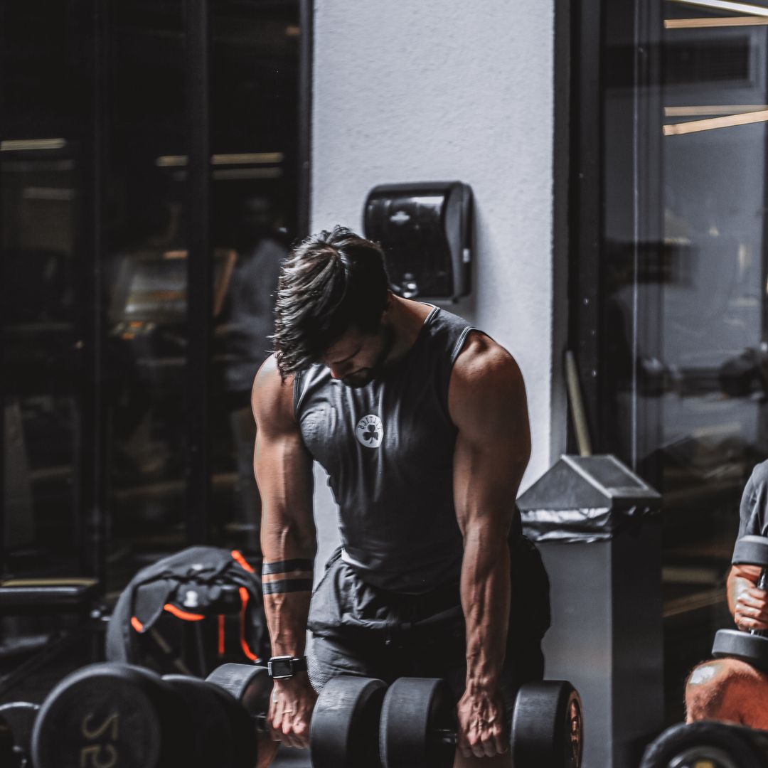 A muscular man doing heavy dumbbell rows in a gym