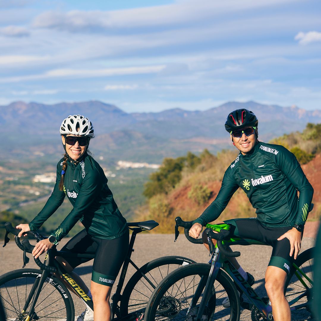 Two smiling cyclists with road bikes posing outdoors before a ride